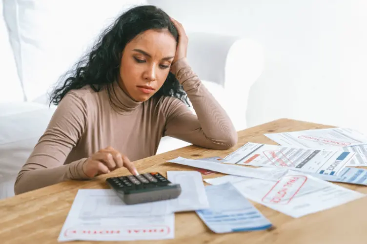 Pessoa calculando dívidas e analisando contas e faturas bancárias enquanto tenta entender o aumento da dívida bancária e os juros aplicados.
